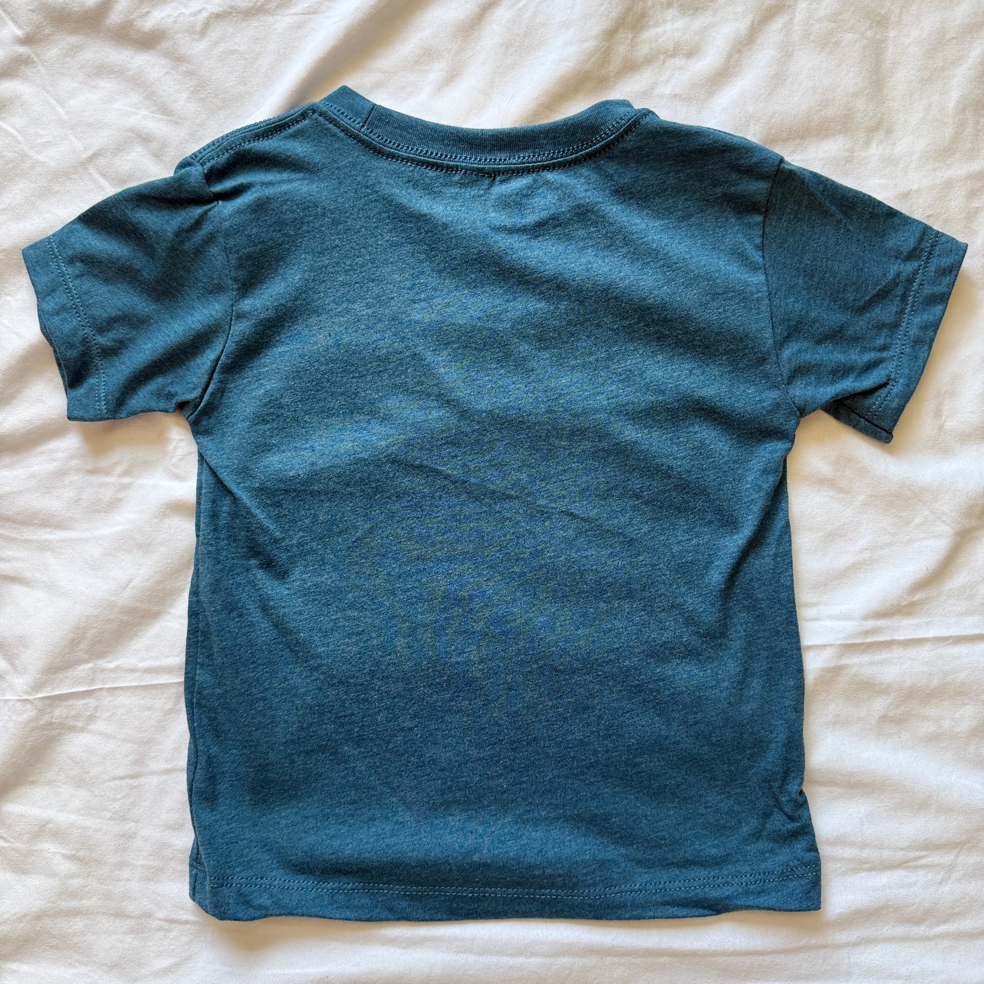 A short-sleeve crewneck t-shirt in a heathered teal blue color, laid flat on a wrinkled white sheet.