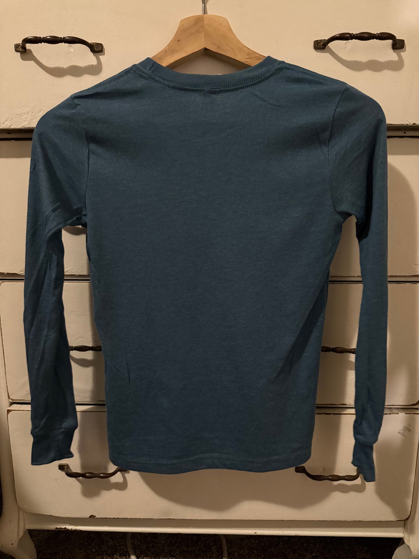 Blue sleeveless shirt on a hanger against a tiled wall background