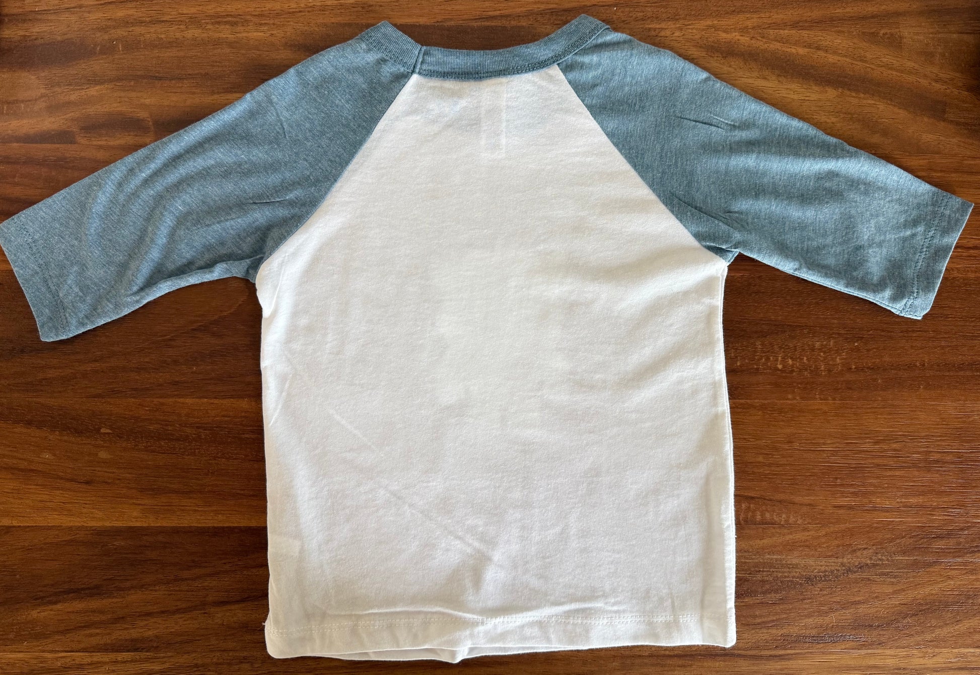 White t-shirt with blue sleeves on a wooden surface