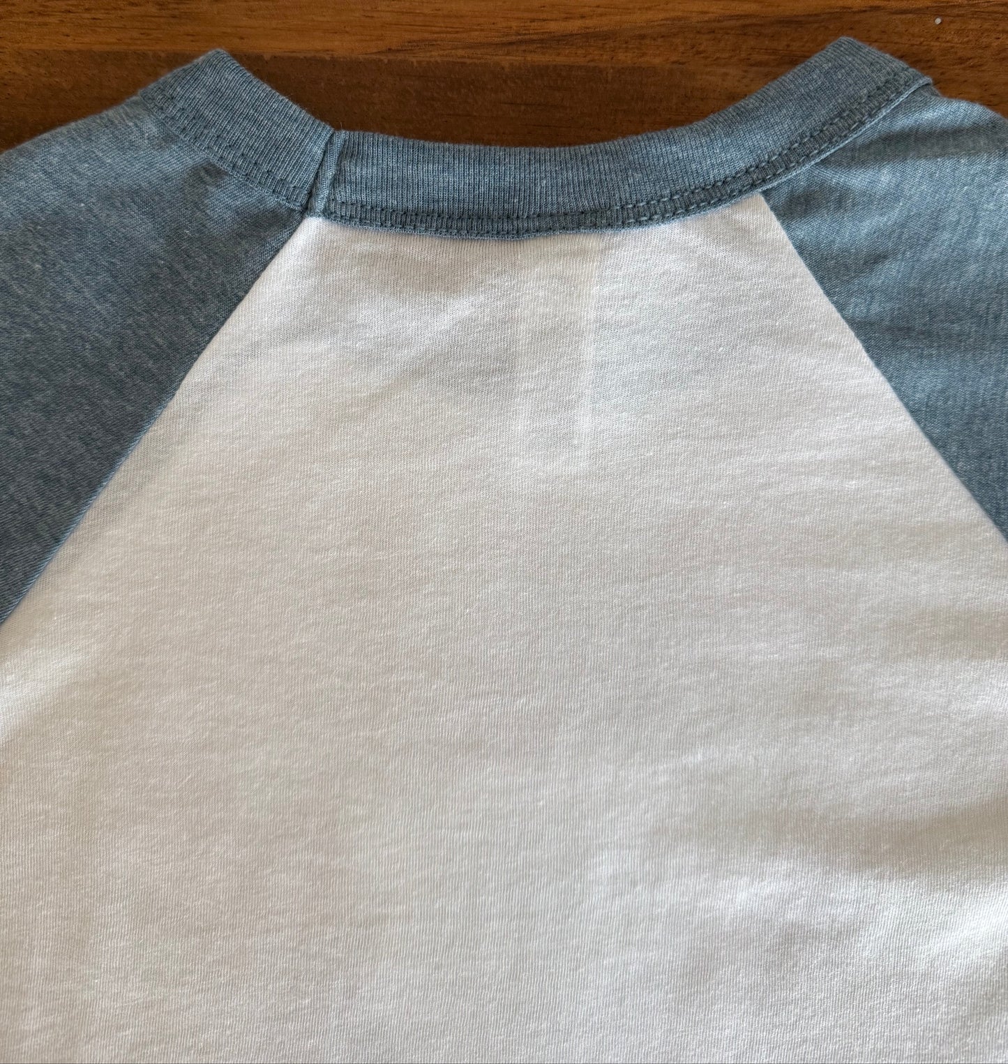 Close-up of a sleeveless shirt with gray sleeves on a wooden surface