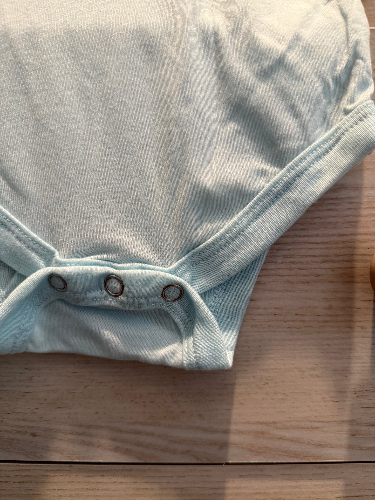 Light blue denim fabric with buttons on a wooden surface