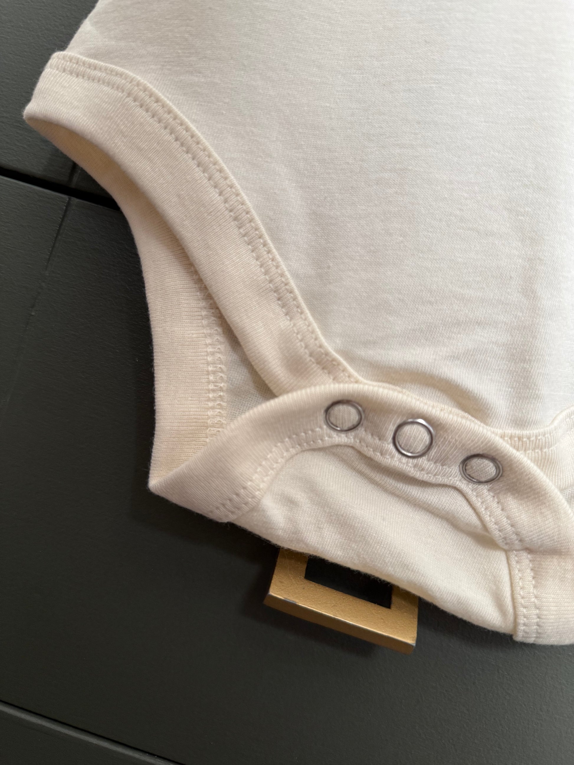 Close-up of a beige baby onesie on a dark surface