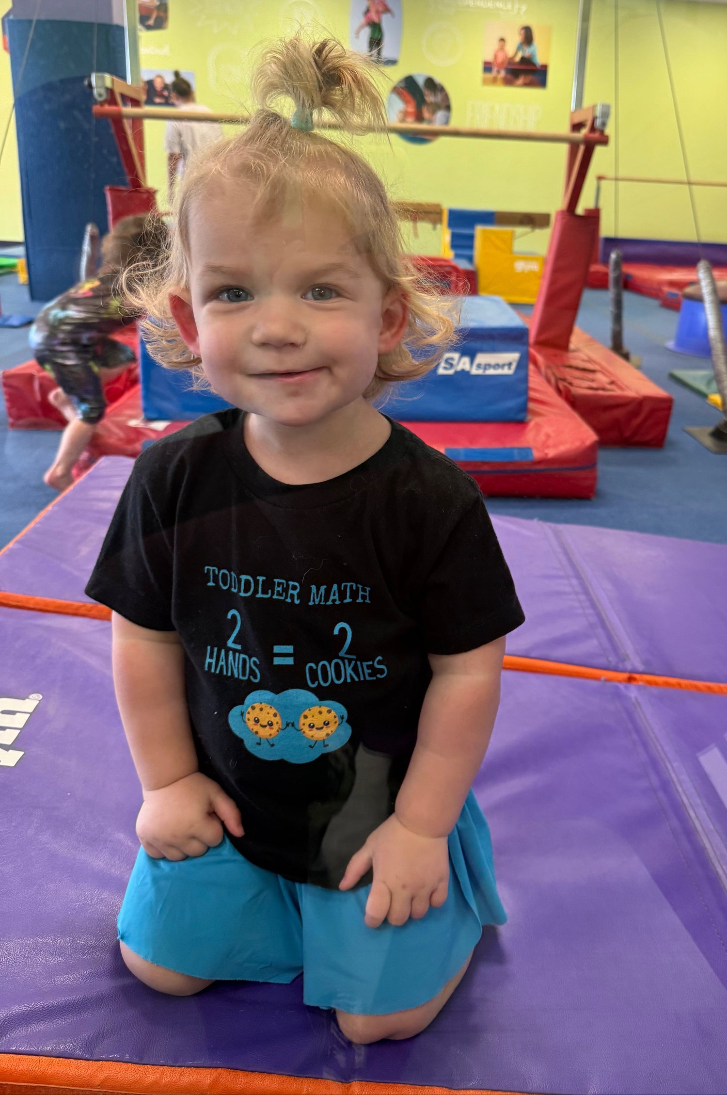 Child in a gymnasium with colorful equipment in the background