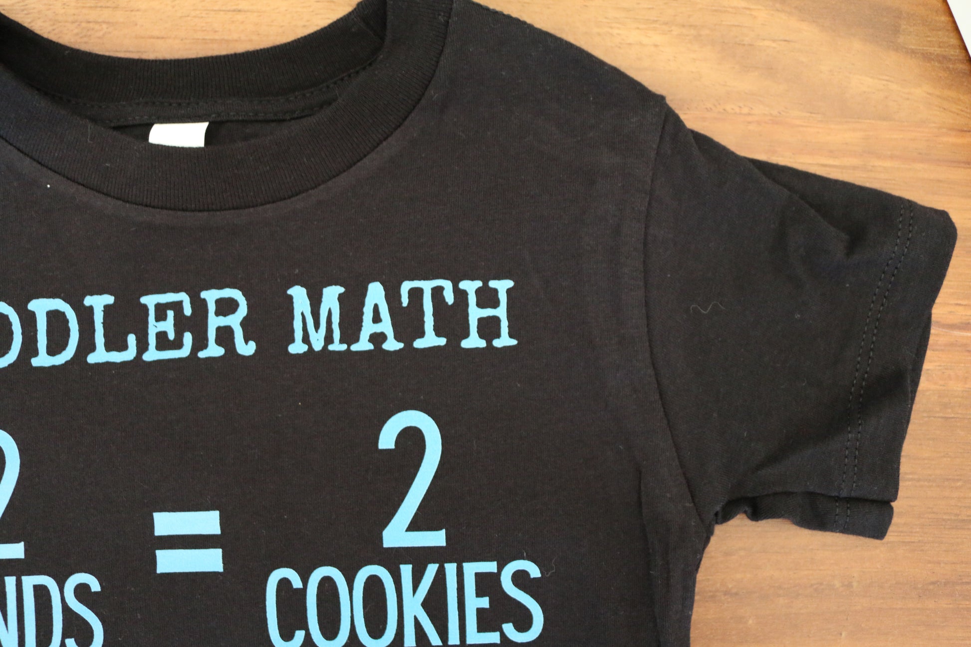 Black t-shirt with turquoise text on a wooden surface